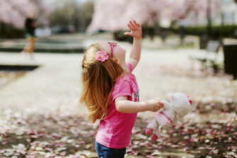 a_girl_standing_under_tree_holding_a_teddybear_photo_unsplash