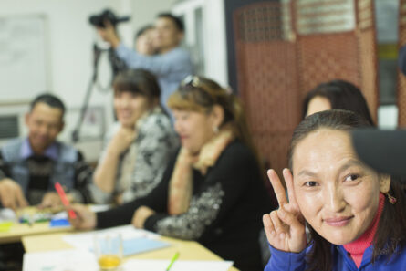 a_deaf_woman_making_victory_sign_with_hands_in_class_photo_Jussi_Valkeajoki.jpg