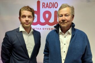 Heikki Vestman ja Esa Ylikoski seisovat Radio Dein logon edessä.